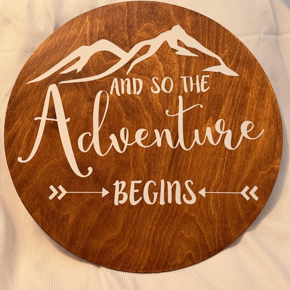 Round Wooden Wall Sign "And So The Adventure Begins" - White on Warm Brown